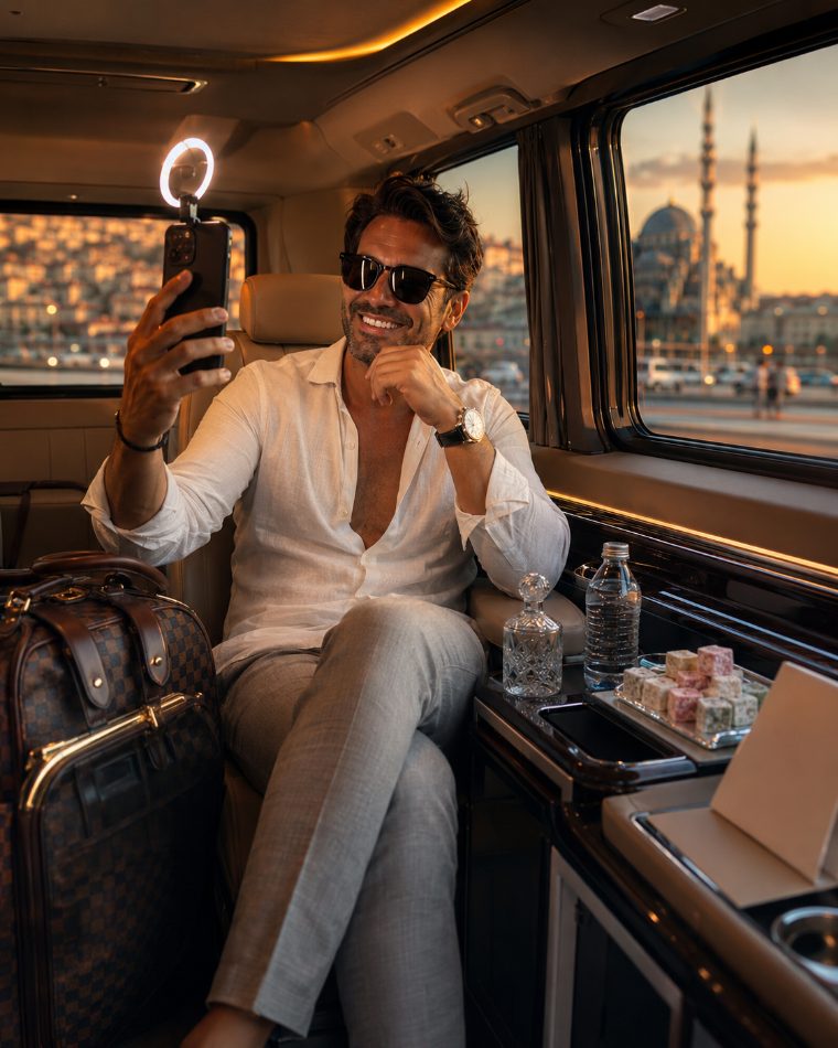 A man films himself with a ring light in the leather back seat of a VIP van